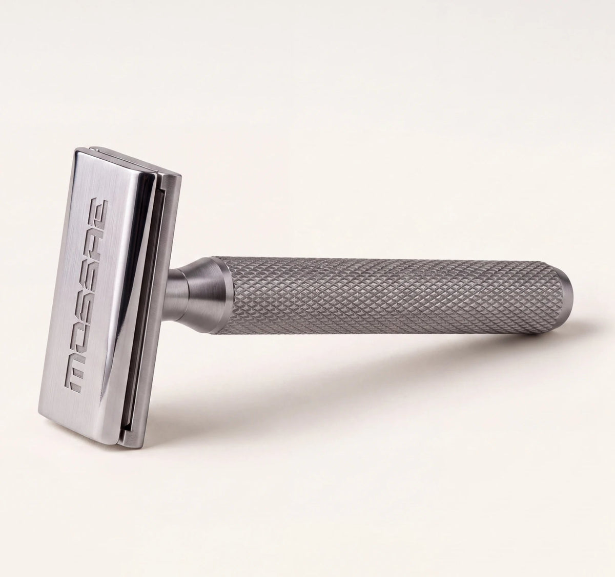 The Mossae razor lying on its side in a grey studio